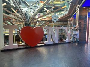 Best things to do in Syracuse - WonderWorks mascot Professor Wonder standing infront of an "I Love NY" sign